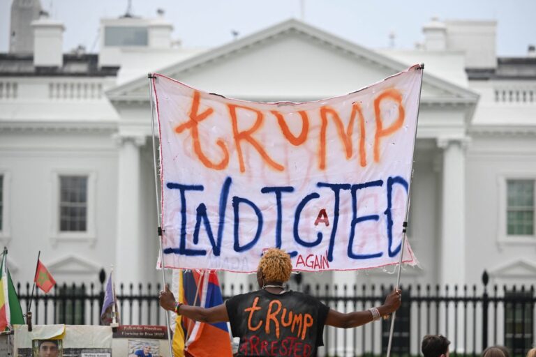 A woman celebrating the indictment of Donald Trump holds a banner in front of the White House in Washington, DC, on June 9, 2023. (MANDEL NGAN/AFP via Getty Images)