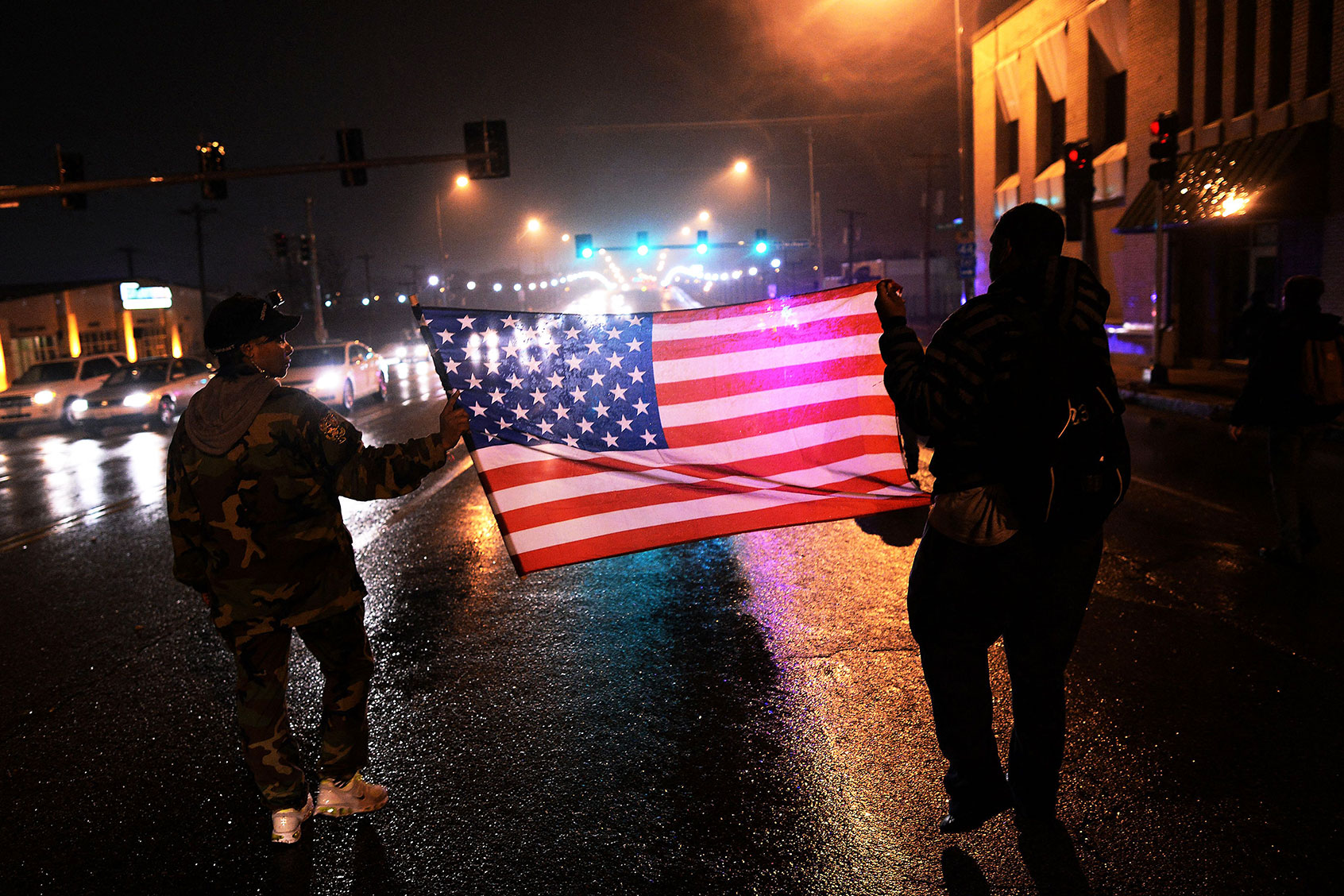 Two demonstrators march with a US flag in St. Louis, Missouri, on November 23, 2014 to protest the death of 18-year-old Michael Brown. (JEWEL SAMAD/AFP via Getty Images)