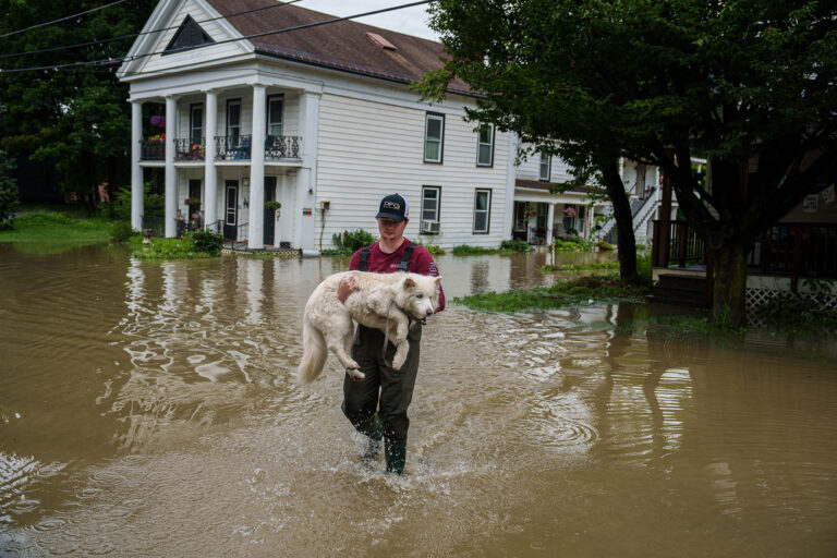 Tyler Jovic, of Montpelier, carries his neighbor's dog to dry ground on Tuesday afternoon, July 11, 2023. Vermont has been under a State of Emergency since Sunday evening as heavy rains continued through Tuesday morning causing flooding across the state. (John Tully for The Washington Post via Getty Images)