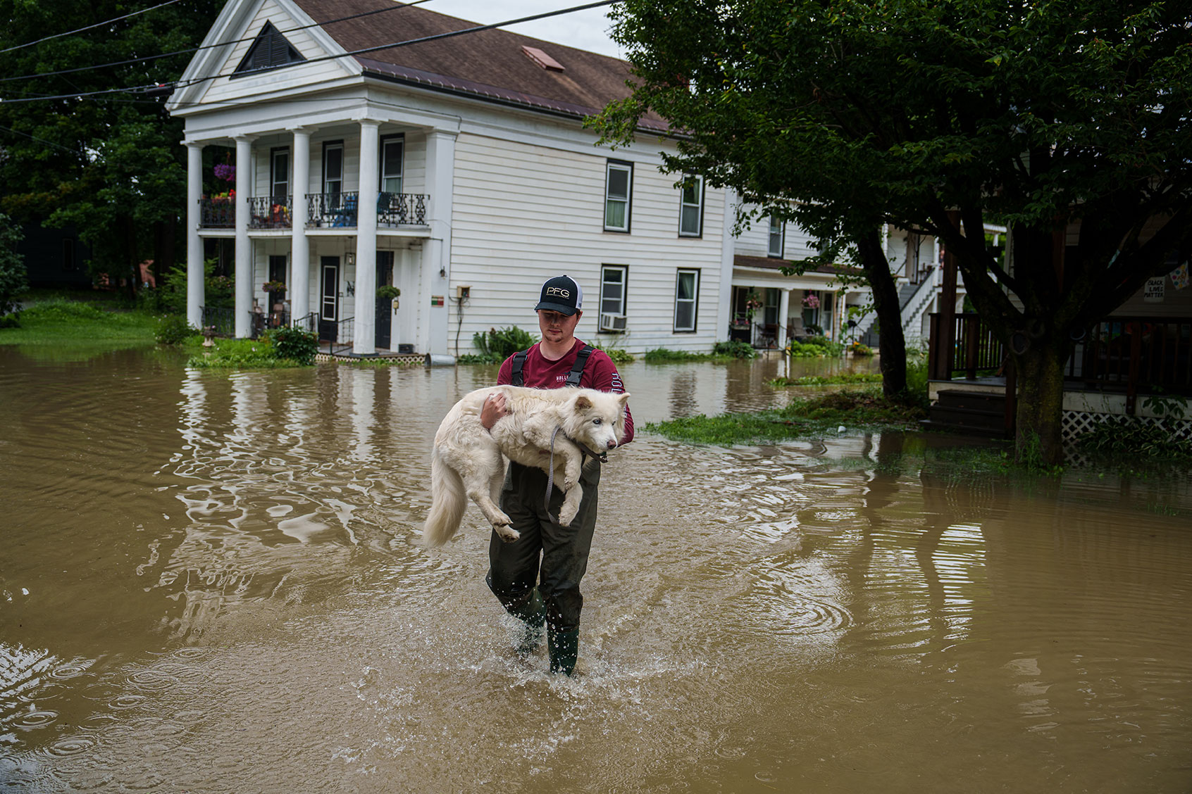 Tyler Jovic, of Montpelier, carries his neighbor's dog to dry ground on Tuesday afternoon, July 11, 2023. Vermont has been under a State of Emergency since Sunday evening as heavy rains continued through Tuesday morning causing flooding across the state. (John Tully for The Washington Post via Getty Images)