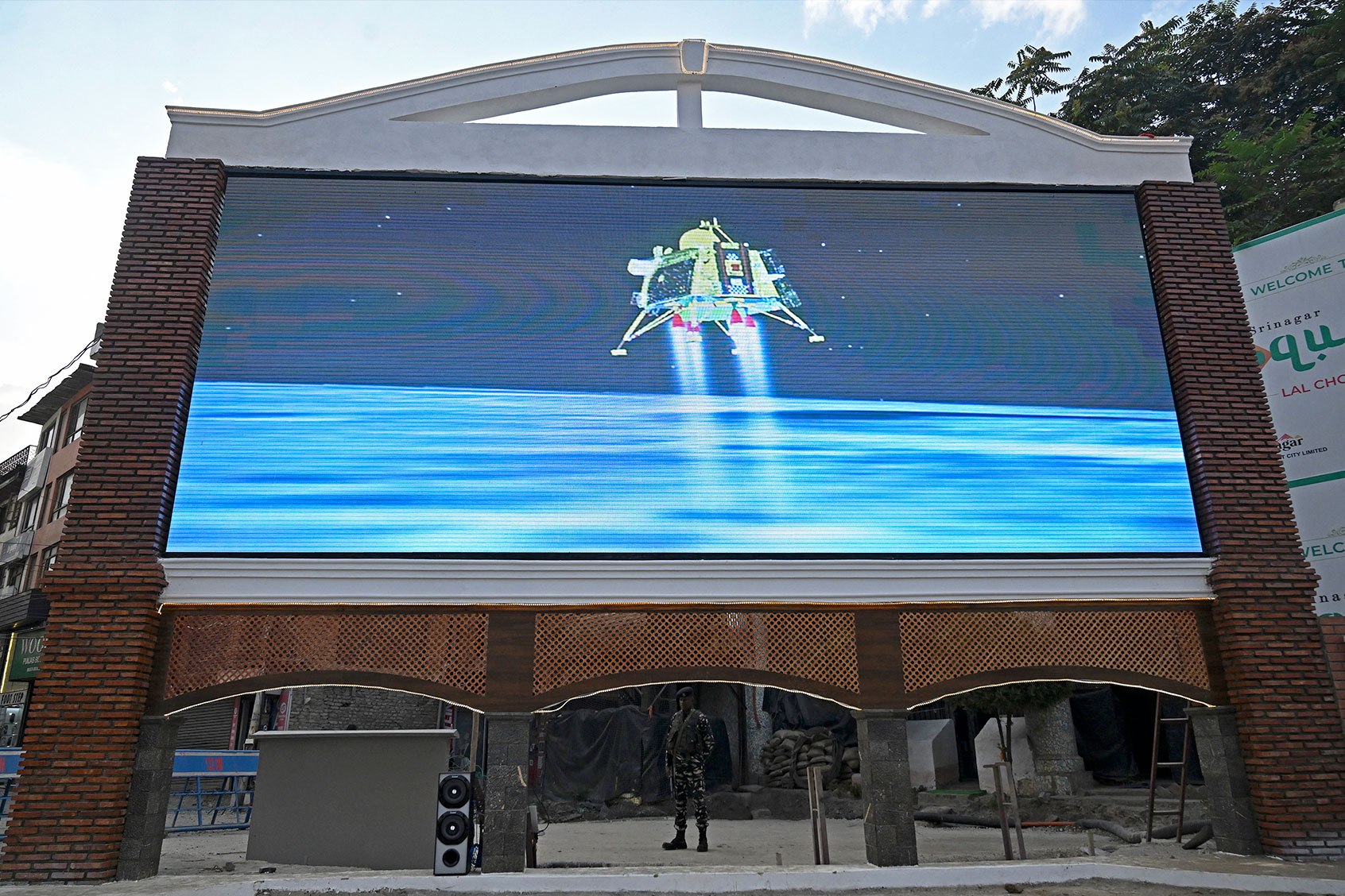 An Indian paramilitary trooper stands guard as a live telecast is aired near a clock tower in Srinagar on August 23, 2023, showing the Chandrayaan-3 spacecraft minutes before its successful lunar landing on the south pole of the Moon. (TAUSEEF MUSTAFA/AFP via Getty Images)