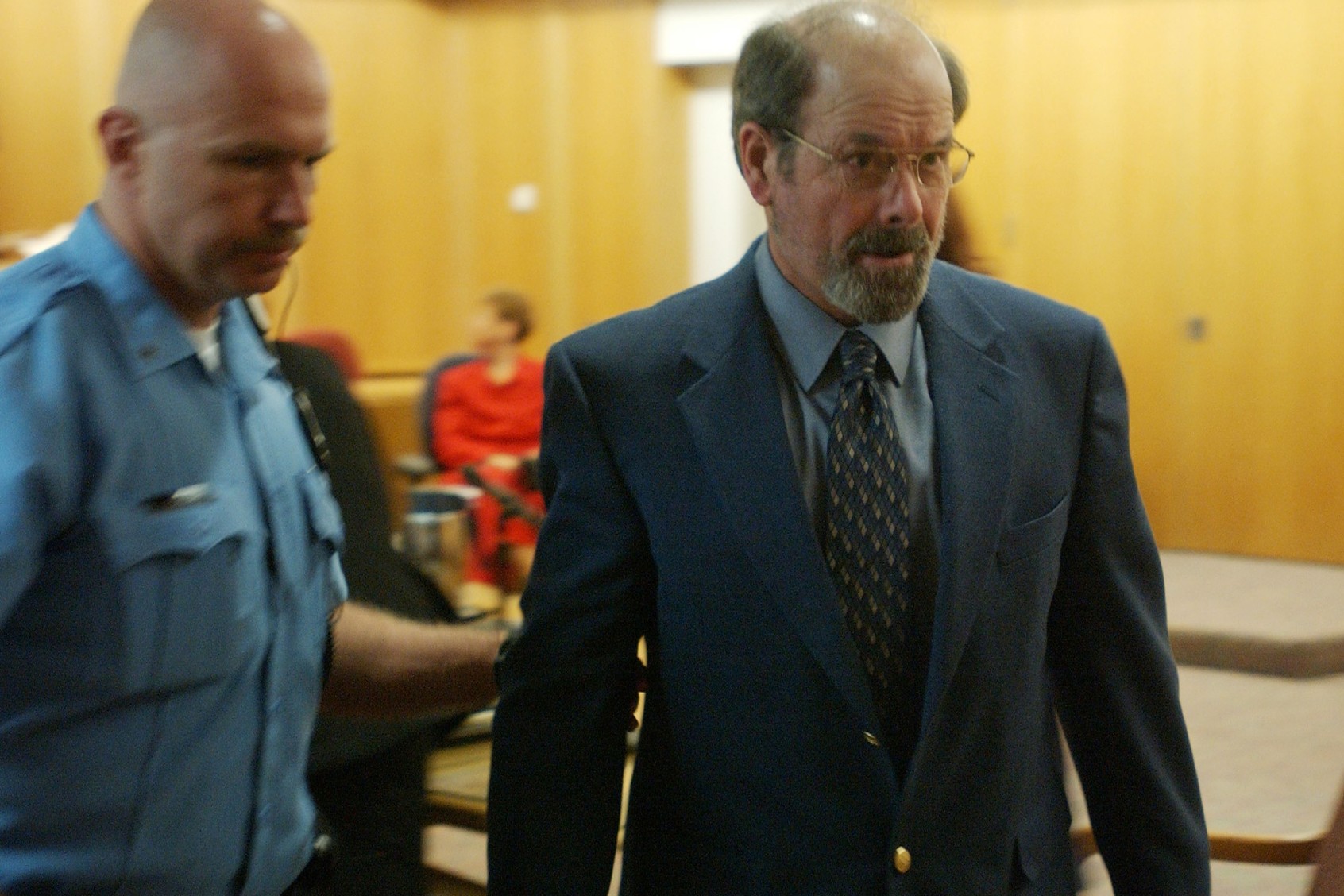 Dennis L. Rader (R), suspected of being the BTK serial killer, is escorted from the Sedgwick County courtroom after his arraignment May 3, 2005 in Wichita, Kansas. Rader, charged with 10 counts of murder, entered a plea of not guilty on all counts. (Bo Rader-Pool/Getty Images)