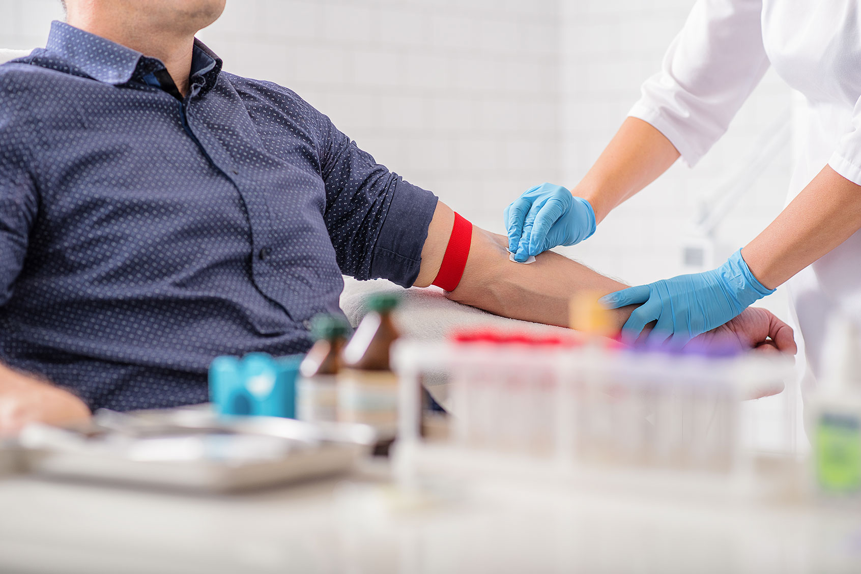 Nurse disinfecting male arm before drawing blood (Getty Images/YakobchukOlena)