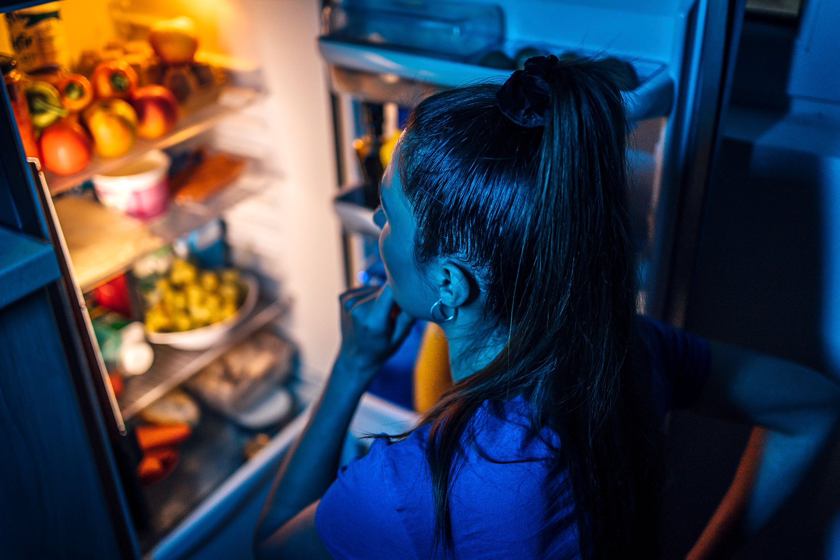 Young woman in front of the refrigerator at night (Getty Images/LordHenriVoton)