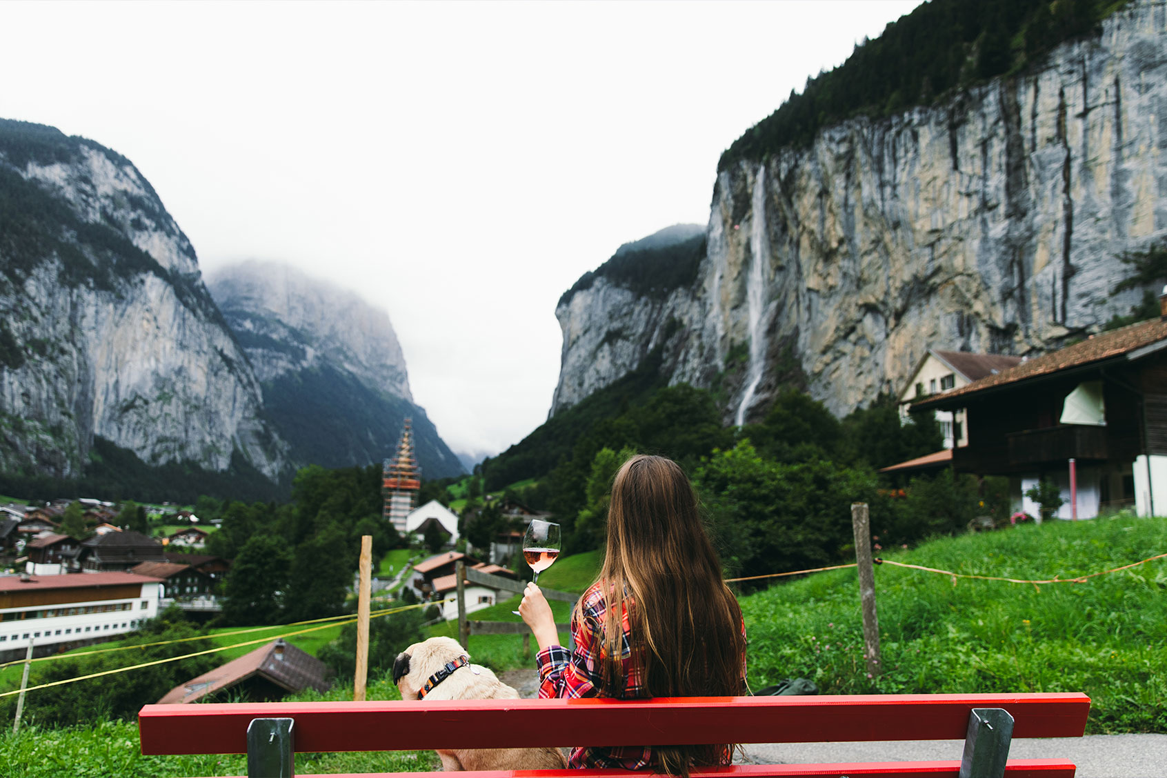 Woman and dog relaxing with a glass of wine with view of waterfall in Lauterbrunnen in the Swiss Alps (Getty Images/Anastasiia Shavshyna)
