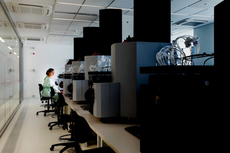 A female scientist sits amid large machinery in a leading medical research center. (Getty Images/SolStock)