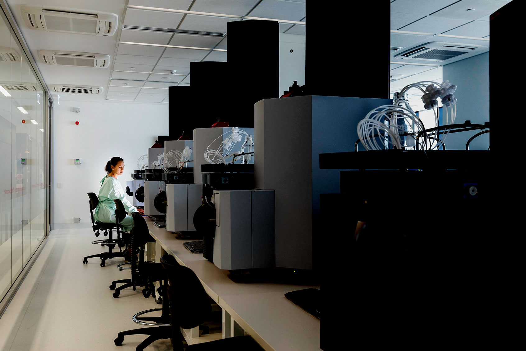 A female scientist sits amid large machinery in a leading medical research center. (Getty Images/SolStock)