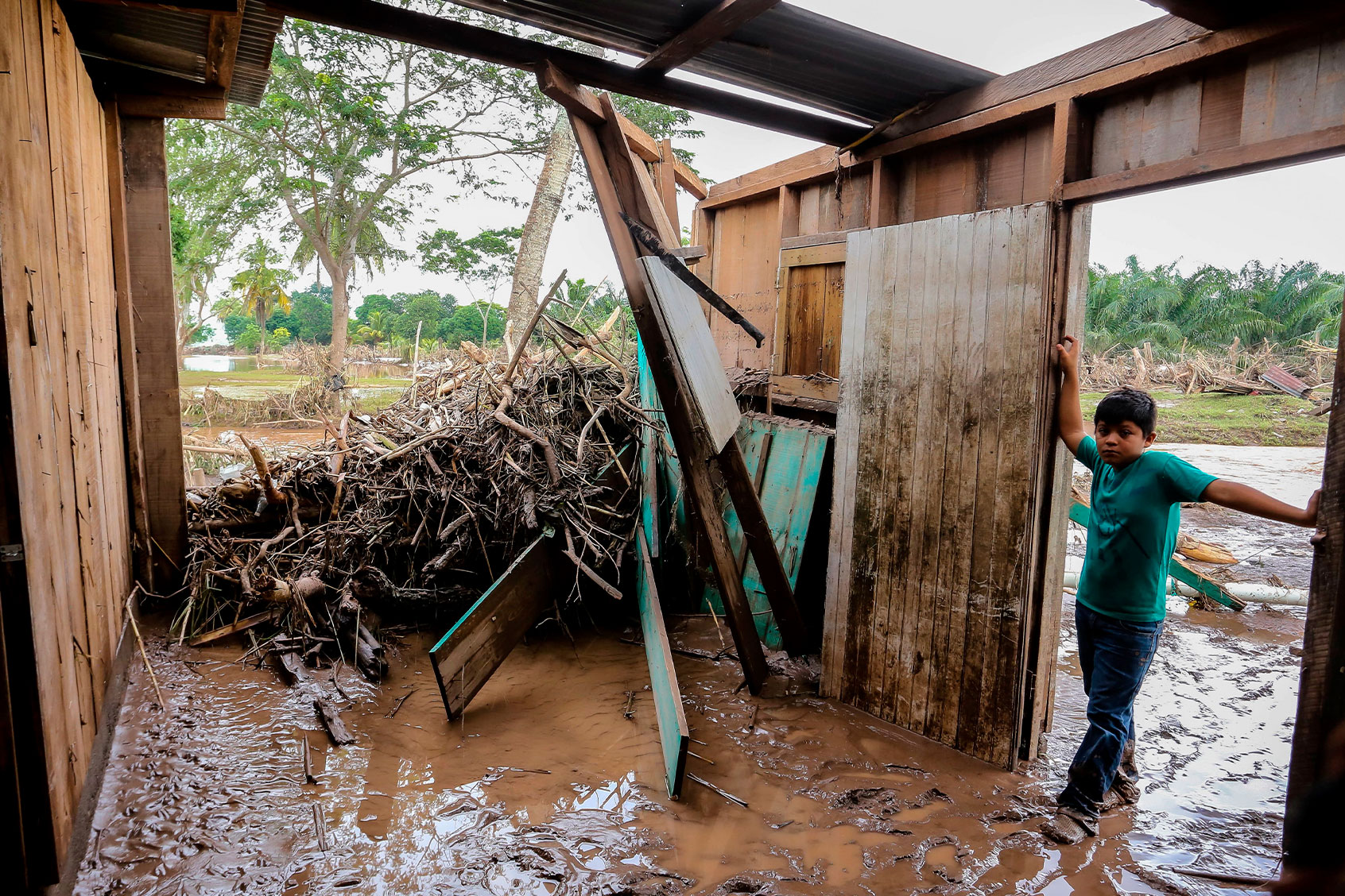 A young boy stands at their home full with mud and debris after the flood caused by Ulua River's overfloow due to heavy heavy rains of Hurricane Iota in Potrerillos municipality near San Pedro Sula, Honduras on November 20, 2020. (WENDELL ESCOTO/AFP via Getty Images)