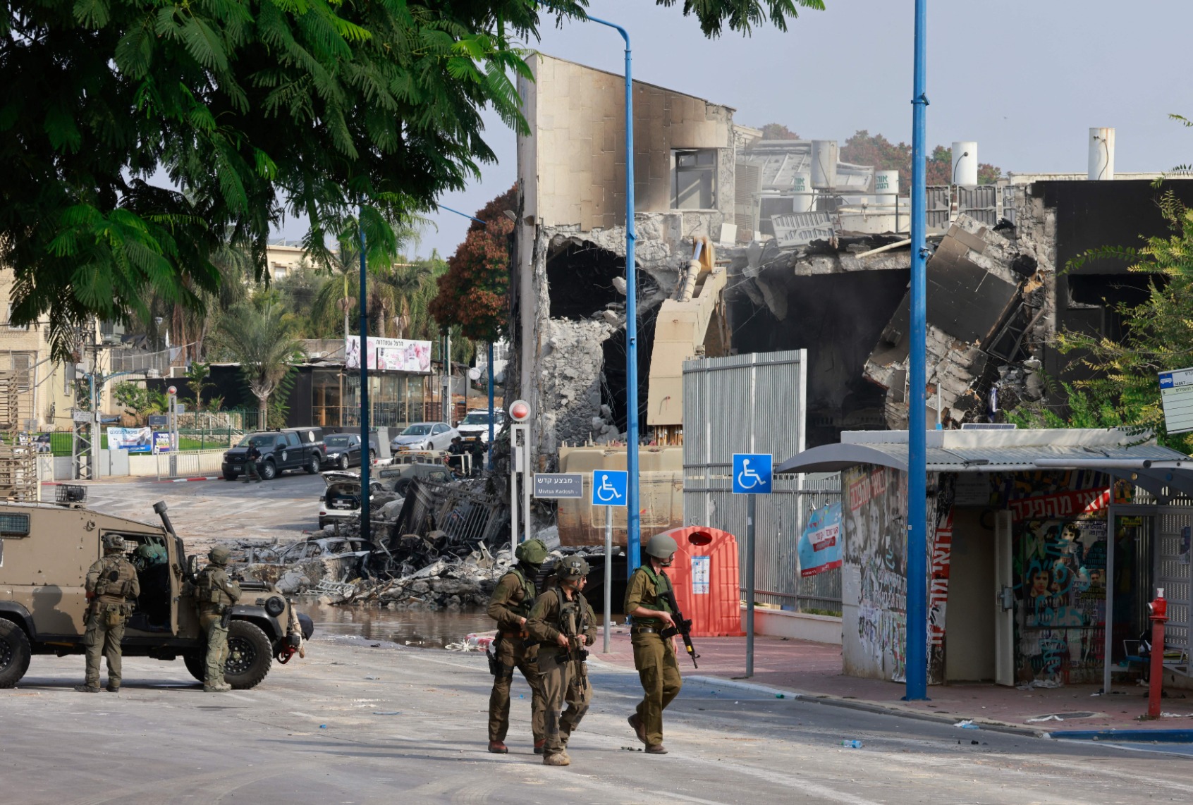 Israeli troops gather around a cordoned-off Israeli police station that was damaged during battles to dislodge Hamas militants who were stationed inside, on October 8, 2023. (MENAHEM KAHANA/AFP via Getty Images)