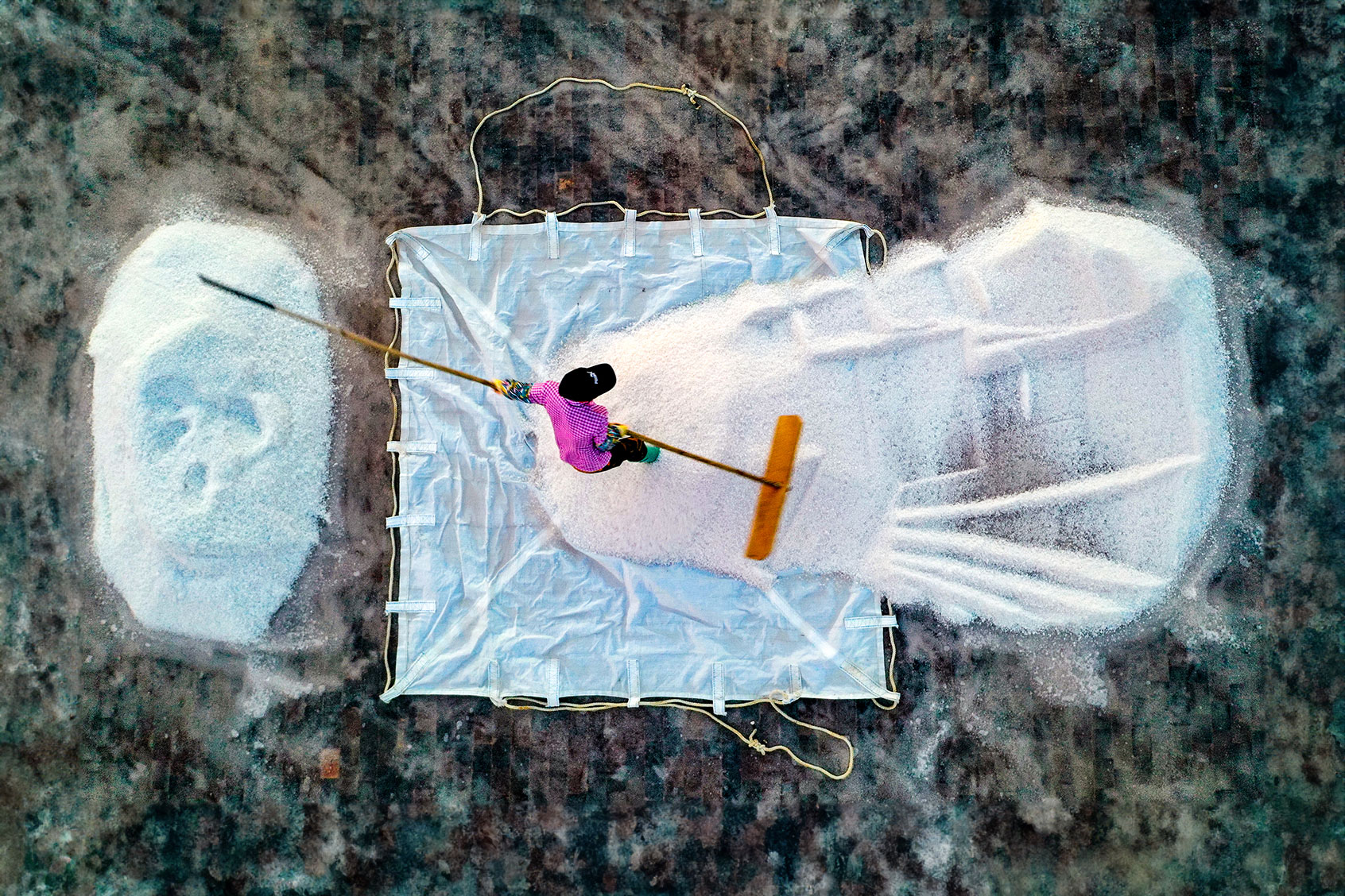 A worker harvests salt from an evaporation pond at a salt factory on May 14, 2021 in Leizhou, Zhanjiang City, Guangdong Province of China. (Zhan Youbing/VCG via Getty Images)