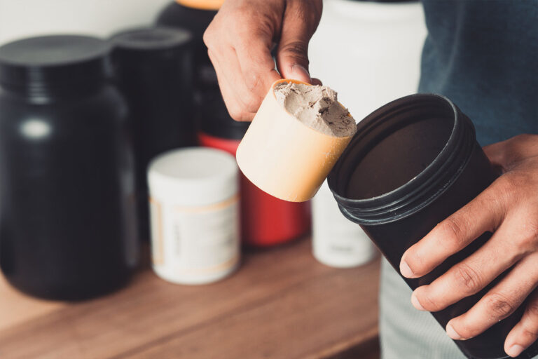 Hands holding scoop of whey protein and shaker (Getty Images/Djavan Rodriguez)