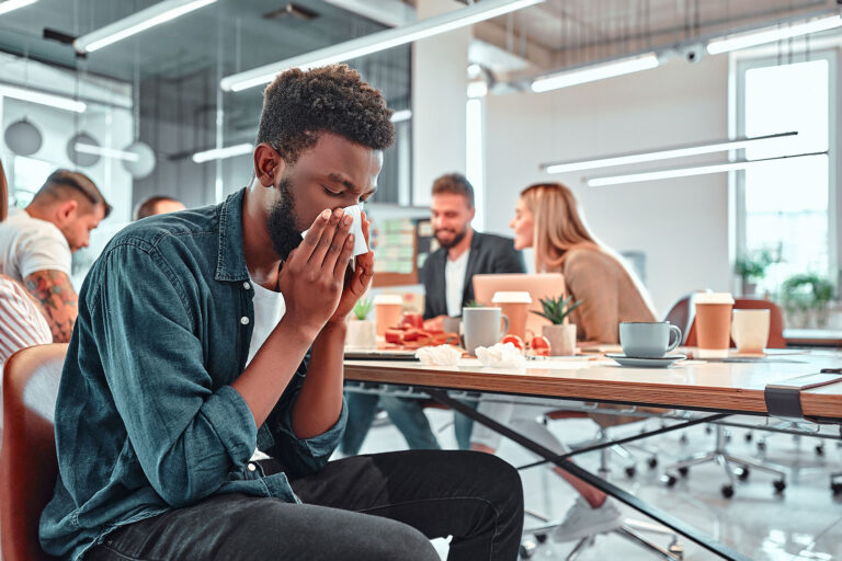 Man ill with flu in office (Getty Images/Harbucks)