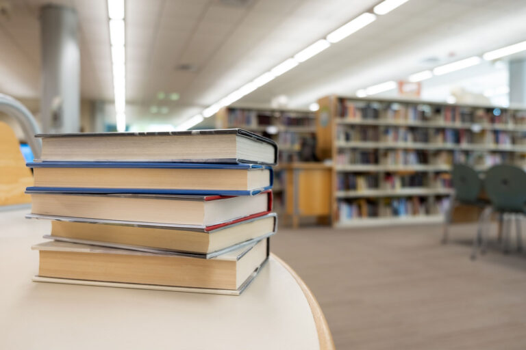 Stack of books on table at library (Getty images/Kenishirotie)