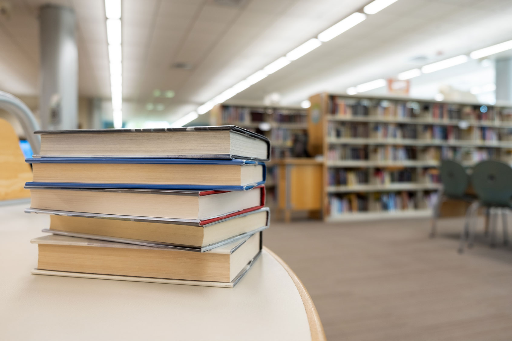 Stack of books on table at library (Getty images/Kenishirotie)