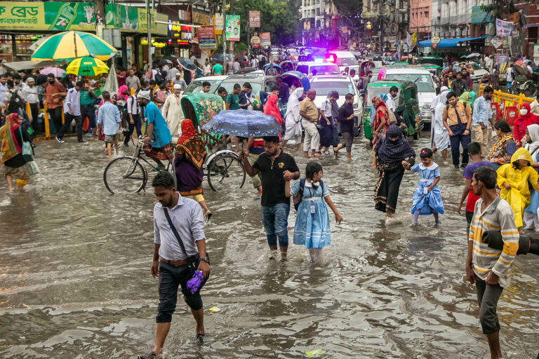 Children cross road after school through the waterlogged streets after heavy rainfalls in Dhaka, Bangladesh on September 05, 2022. (Kazi Salahuddin Razu/NurPhoto via Getty Images)