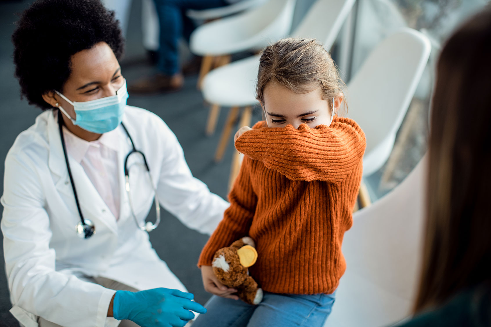 Little girl coughing into elbow while being at medical clinic (Getty Images/Drazen Zigic)