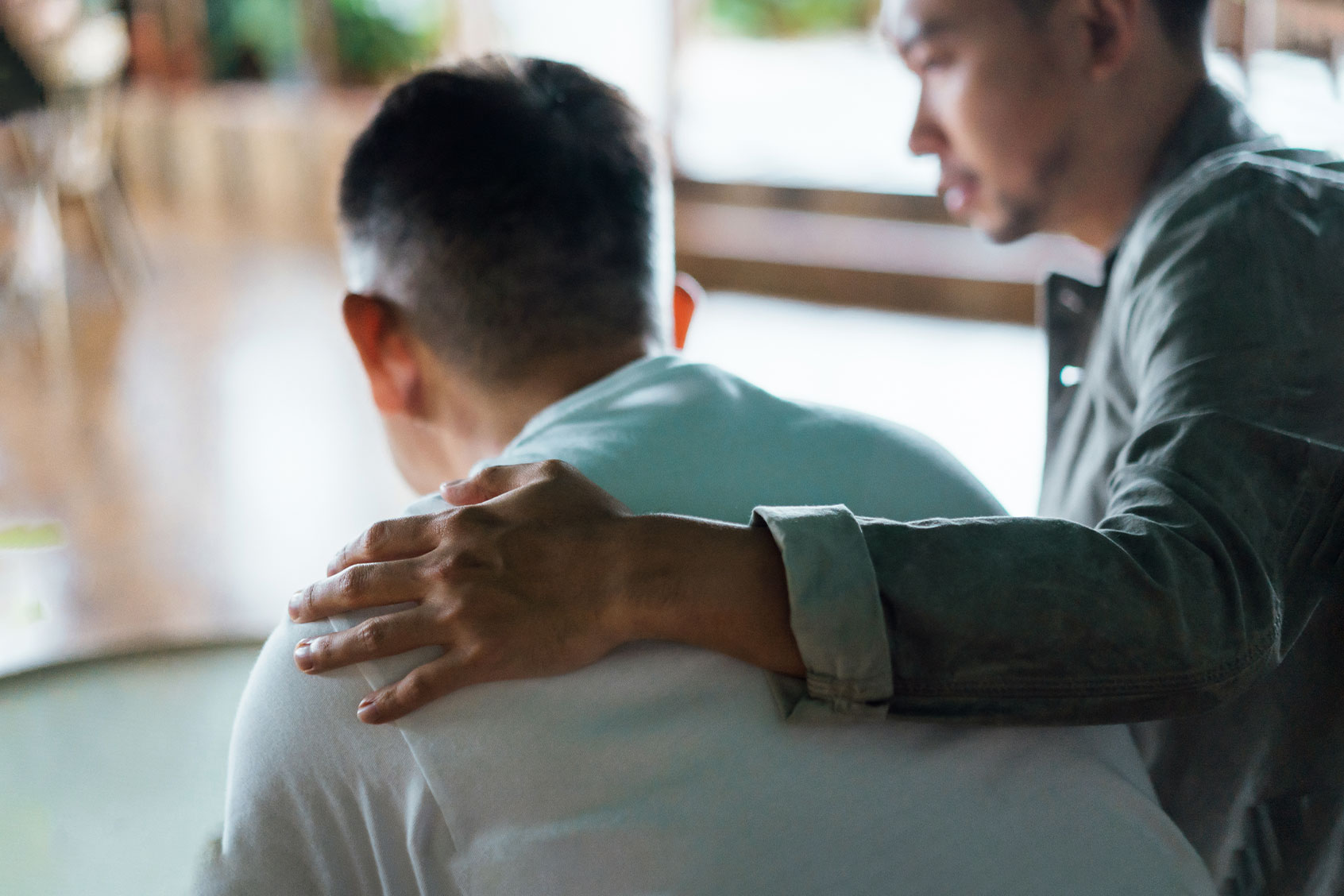 Son caring for his father, putting hand on his shoulder, comforting and consoling him. (Getty Images/AsiaVision)