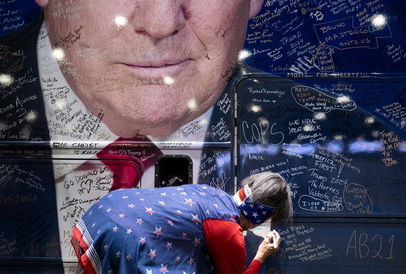 A person signs a bus wrapped with an image of former President Donald Trump during the Conservative Political Action Conference (CPAC) in National Harbor, Maryland, on February 22, 2024. (BRENDAN SMIALOWSKI/AFP via Getty Images)