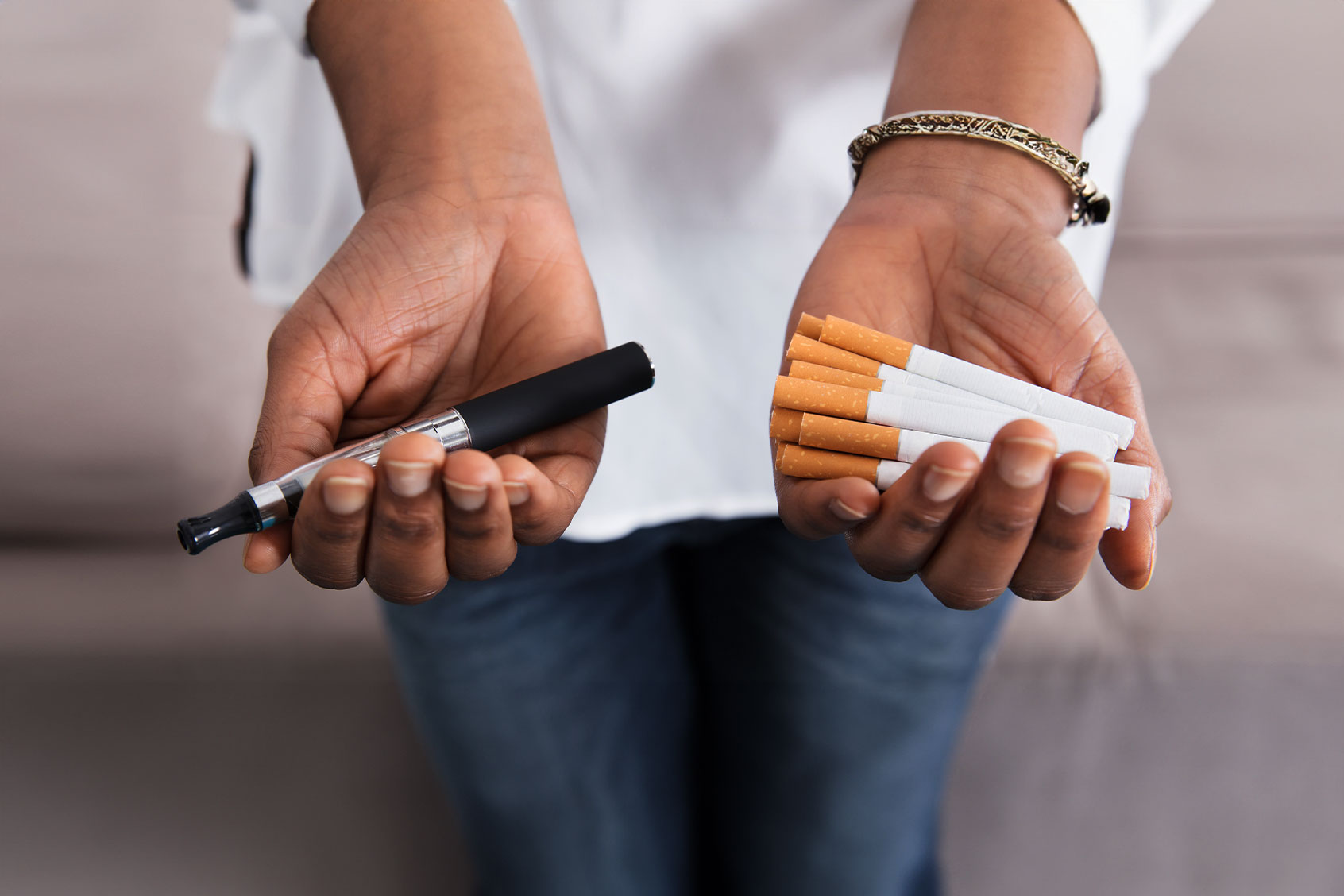 Close-up Of Hands Holding A Vape And Cigarettes (Getty Images/AndreyPopov)