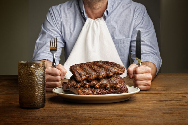 Man about to eat large stack of ribs (Getty Images/RF Pictures)