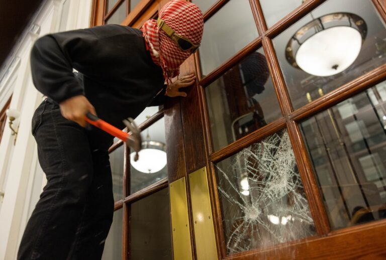 A demonstrator breaks the windows of the front door of the building in order to secure a chain around it to prevent authorities from entering on Tuesday, April 30, 2024 in New York City. (Alex Kent/Getty Images)