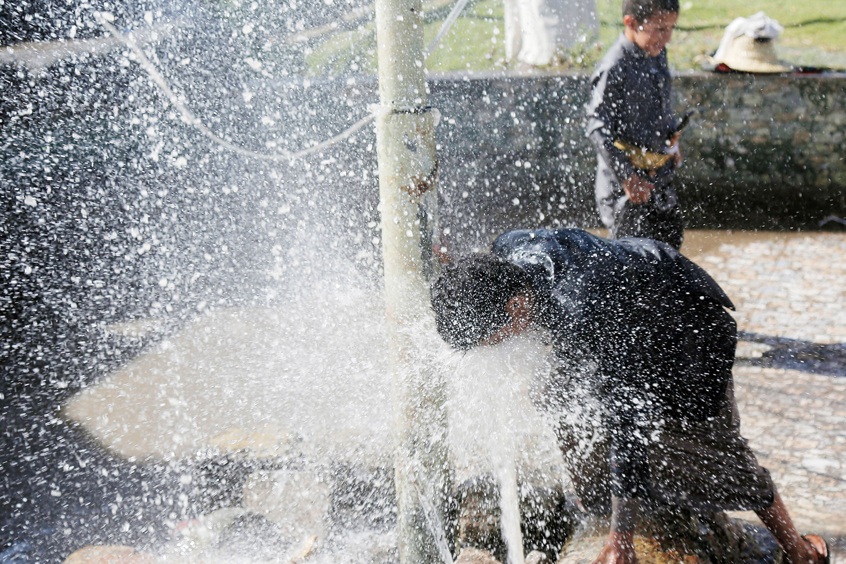 A Yemeni man washes his face under a fountain to cope with the hot weather on March 22, 2024, in Sana'a, Yemen. (Mohammed Hamoud/Getty Images)