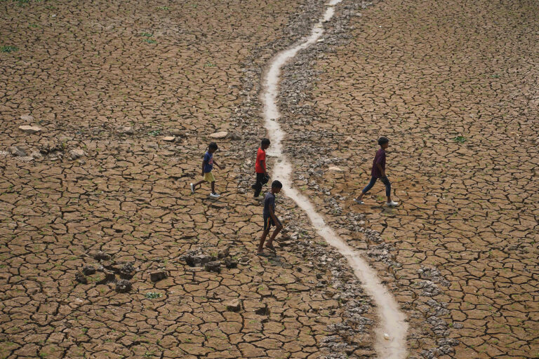 Children are crossing a dried-up lake at Boklung near Kathiatoli in Nagaon District, Assam, India, on April 13, 2024. (Anuwar Hazarika/NurPhoto via Getty Images)