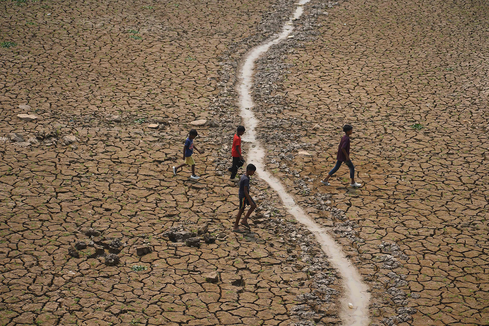 Children are crossing a dried-up lake at Boklung near Kathiatoli in Nagaon District, Assam, India, on April 13, 2024. (Anuwar Hazarika/NurPhoto via Getty Images)