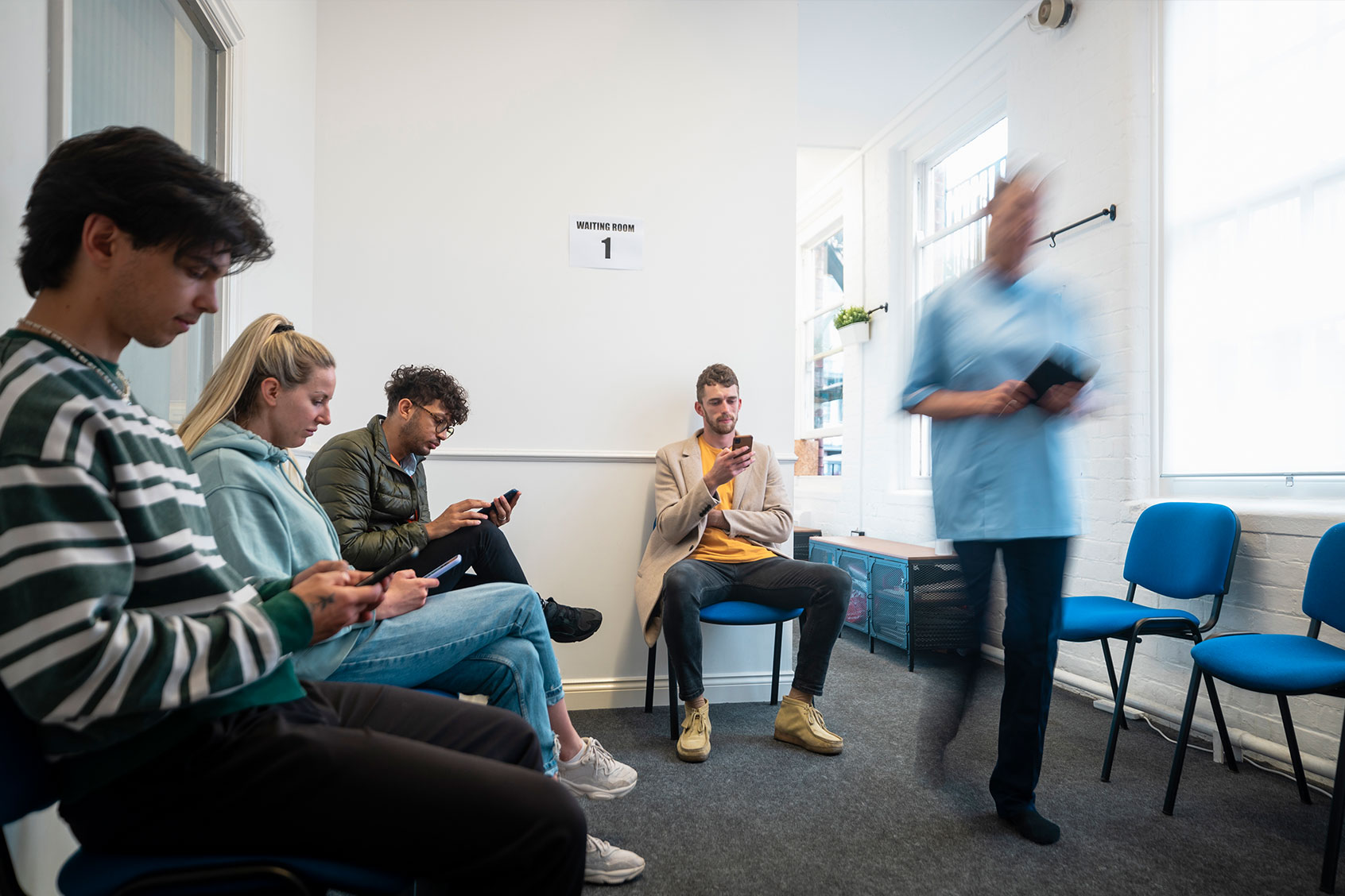People sitting in a doctor office waiting room. (Getty Images/SolStock)