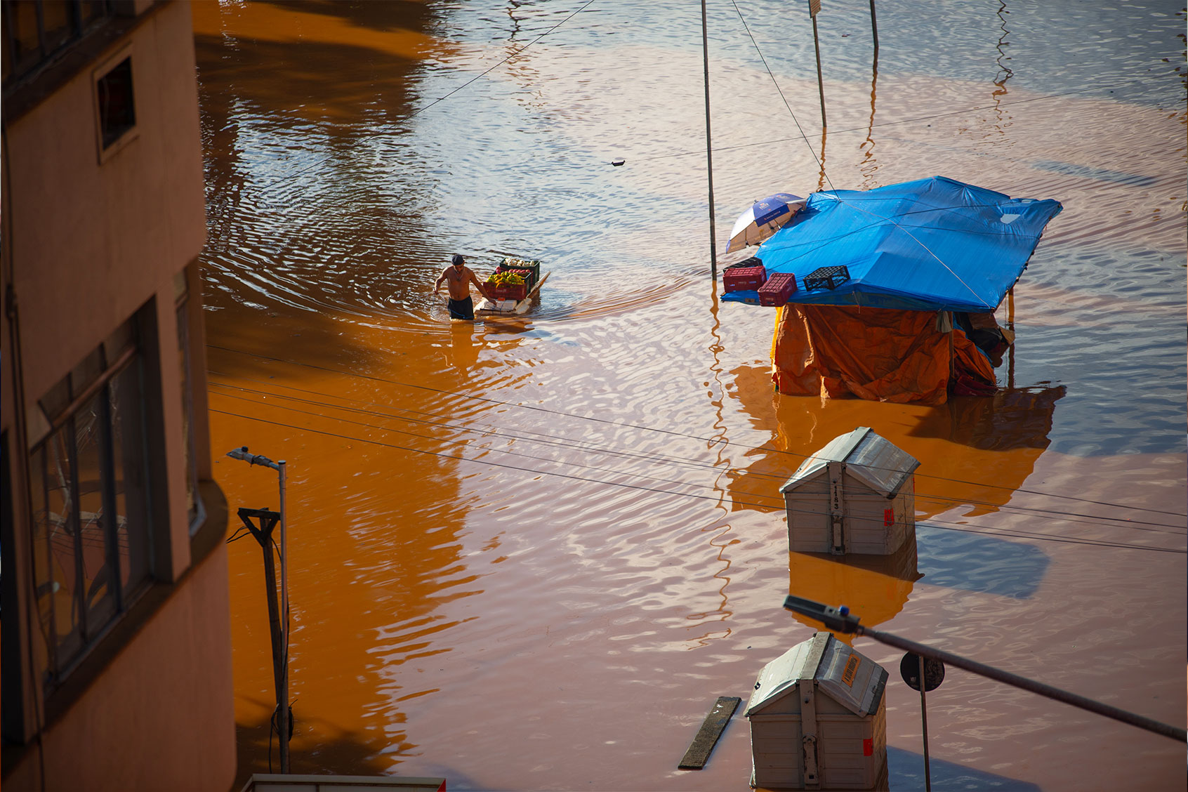 A person carries vegetables and fruits through a flooded street after the overflow of the Guaiba river at downtown on May 5, 2024 in Porto Alegre, Brazil. (Matheus Piccini/Getty Images)