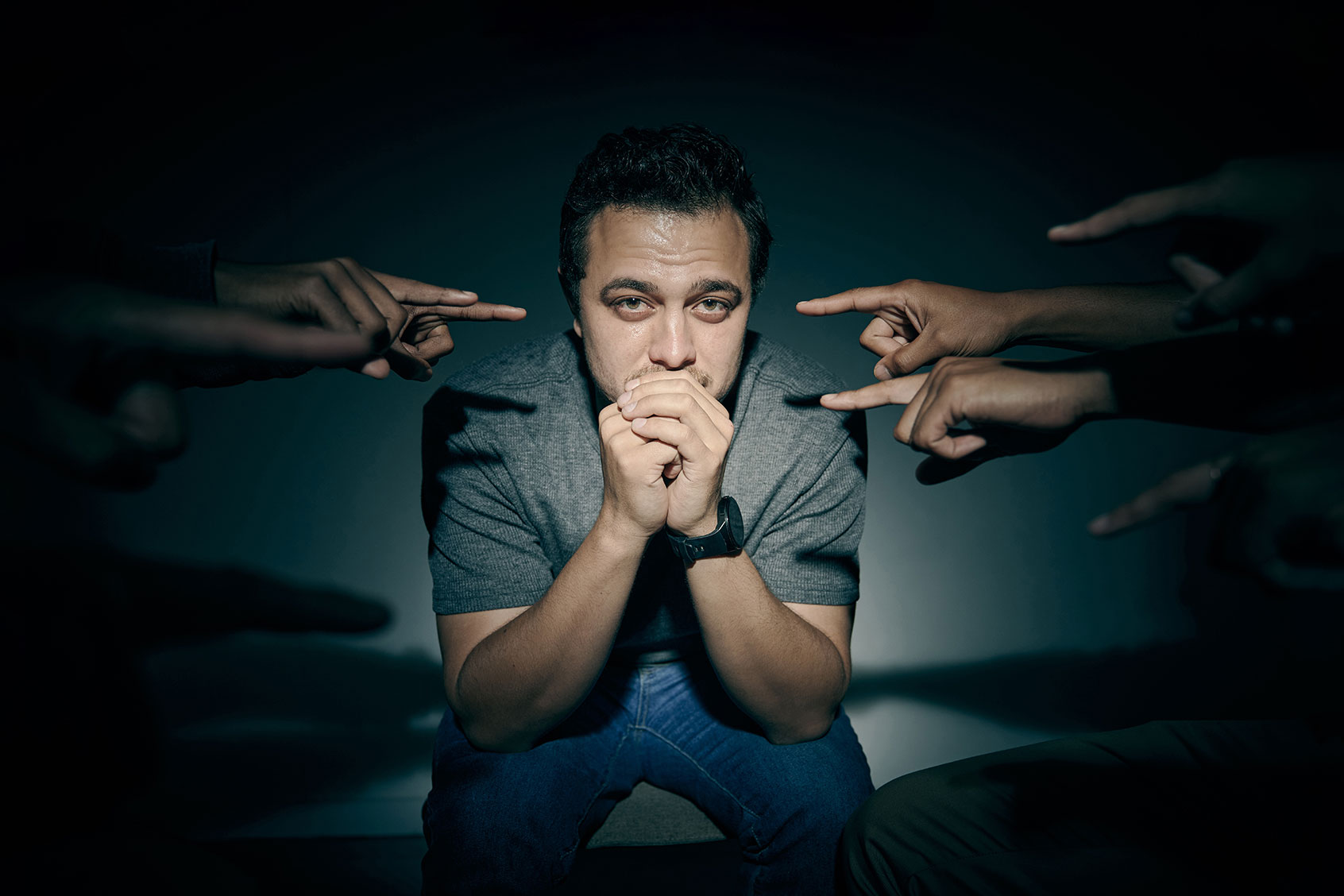 Man stressed out while being surrounded by people pointing at him (Getty Images/PeopleImages)