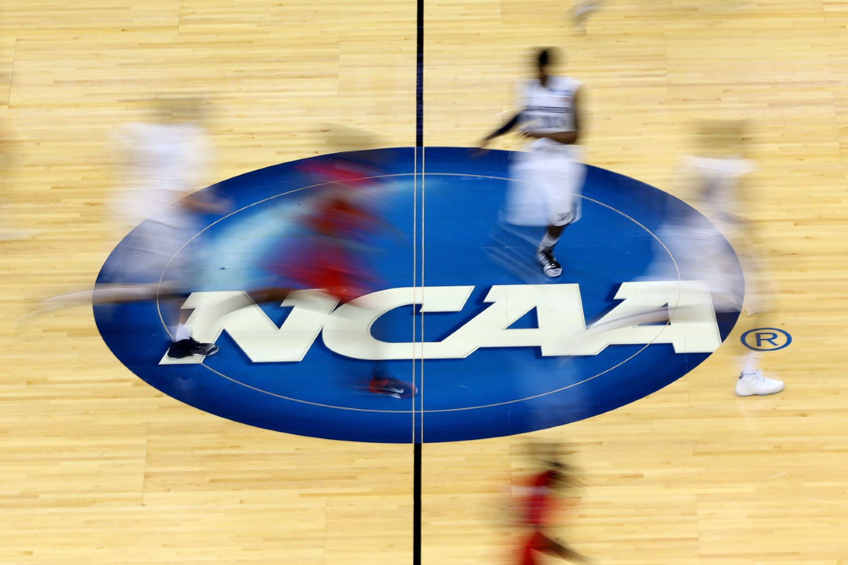 Mississippi Rebels and Xavier Musketeers players run by the logo at mid-court during the second round of the 2015 NCAA Men's Basketball Tournament at Jacksonville Veterans Memorial Arena on March 19, 2015 in Jacksonville, Florida. (Mike Ehrmann/Getty Images)