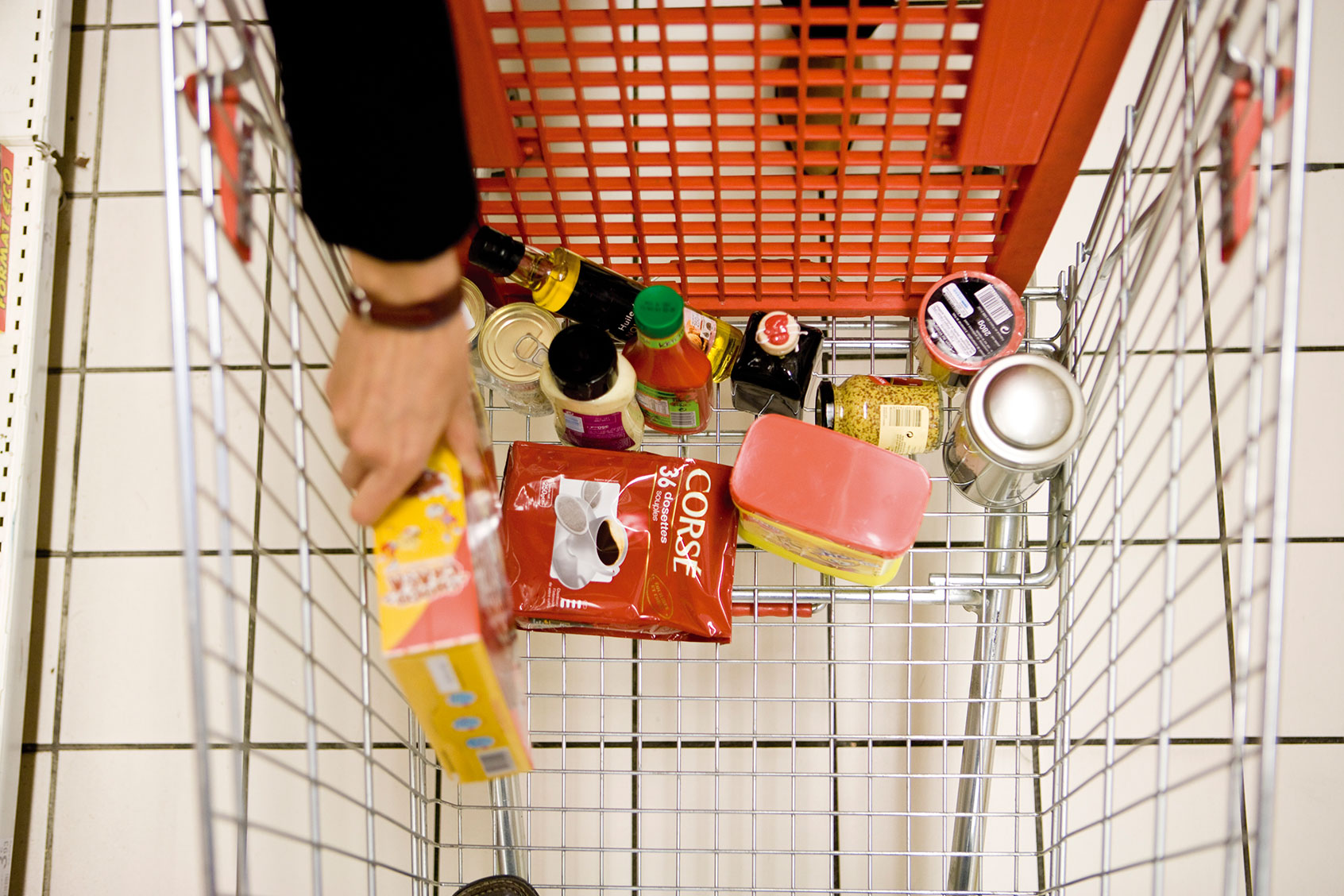 Shopper placing groceries in shopping cart (Getty Images/PhotoAlto/James Hardy)