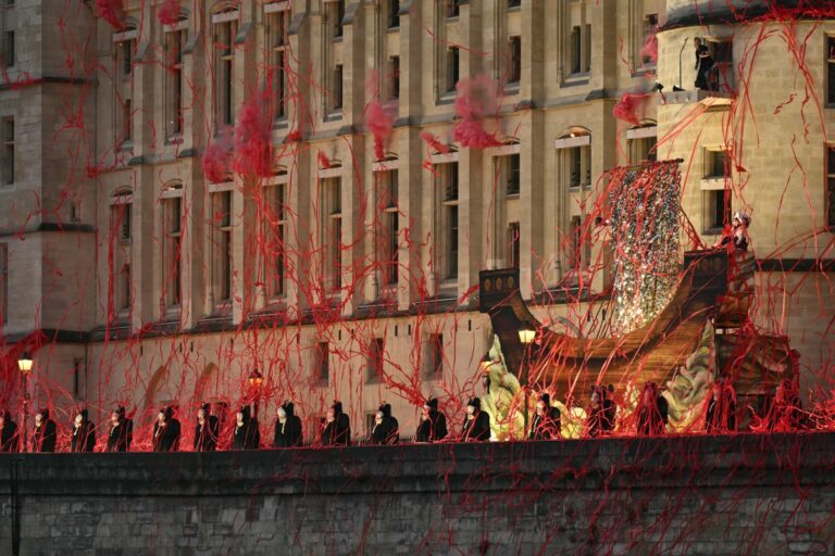Headless figures depicting the 18th century Queen Marie Antoinette perform along the Seine river embankment outside the Conciergerie, where the queen was held captive during the French Revolution, during the Paris 2024 Olympics opening ceremony on July 26, 2024. (NATALIA KOLESNIKOVA/AFP via Getty Images)