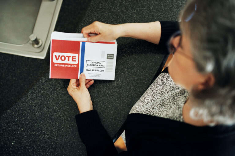 Mature woman reading instructions on a vote by mail ballot at home (Getty Images/AJ_Watt)