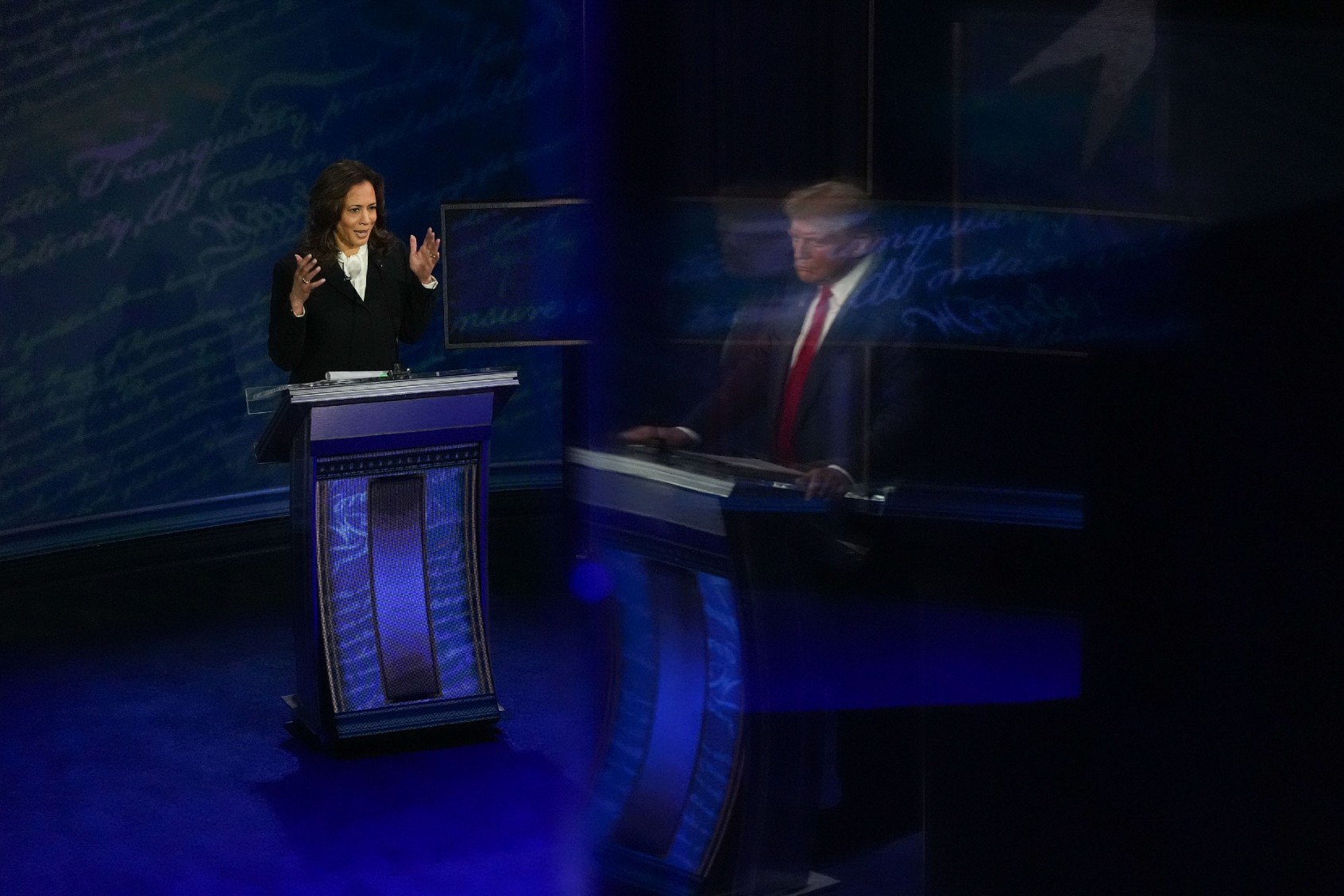 Former President and Republican presidential candidate Donald Trump, reflected on a wall, and Vice President and Democratic presidential candidate Kamala Harris during the first presidential debate at National Constitution Center in Philadelphia, PA on Tuesday, Sept. 10, 2024. (Demetrius Freeman/The Washington Post via Getty Images)