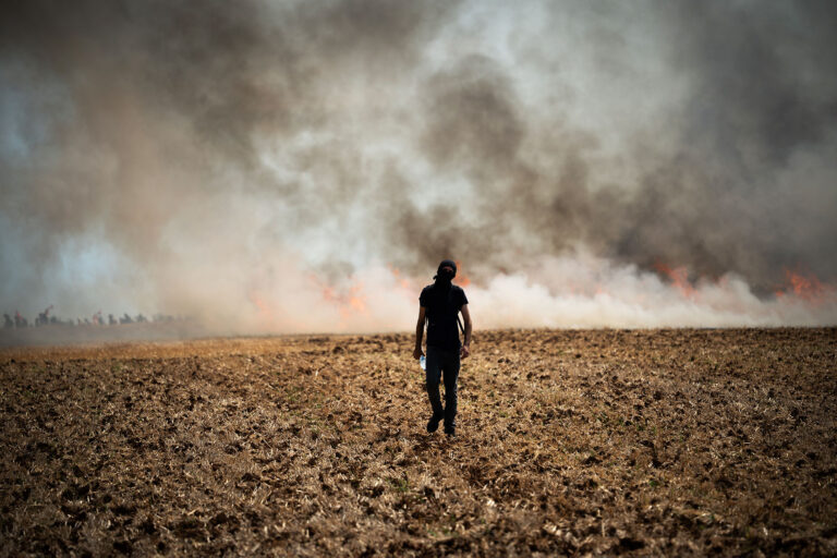 A protester is walking towards a wildfire started by a launched tear gas canister during a march as part of a rally against the construction of a giant water reservoir (mega-bassine) in Migne-Auxances, western France, on July 19, 2024. (Jerome Gilles/NurPhoto via Getty Images)