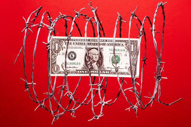 US dollar bill inside coil of steel barbed wire (Getty Images/PM Images)