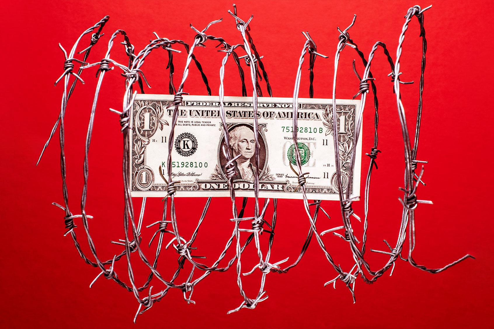 US dollar bill inside coil of steel barbed wire (Getty Images/PM Images)