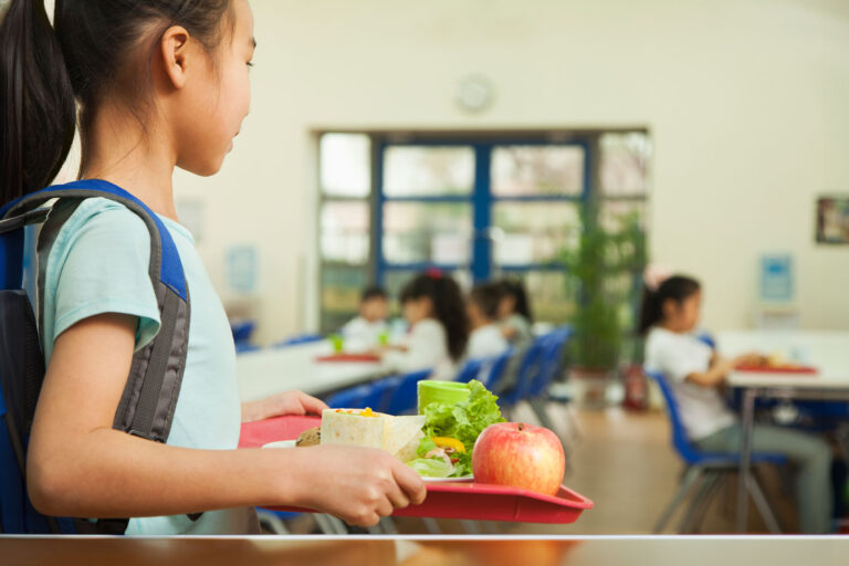 School girl holding food tray in school cafeteria (Getty Images/XiXinXing)