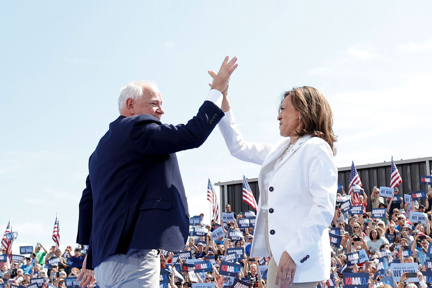 US Vice President and 2024 Democratic presidential candidate Kamala Harris and her running mate Minnesota Governor Tim Walz high-five as they arrive for a campaign rally in Eau Claire, Wisconsin, August 7, 2024. (KAMIL KRZACZYNSKI/AFP via Getty Images)