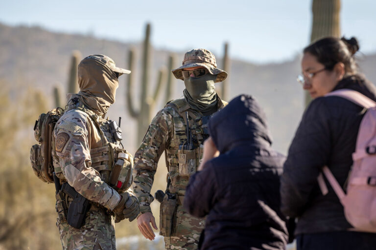 U.S. Border Patrol agents watch over immigrant families waiting to be transported from the U.S.-Mexico border on December 07, 2023 in Lukeville, Arizona. (John Moore/Getty Images)