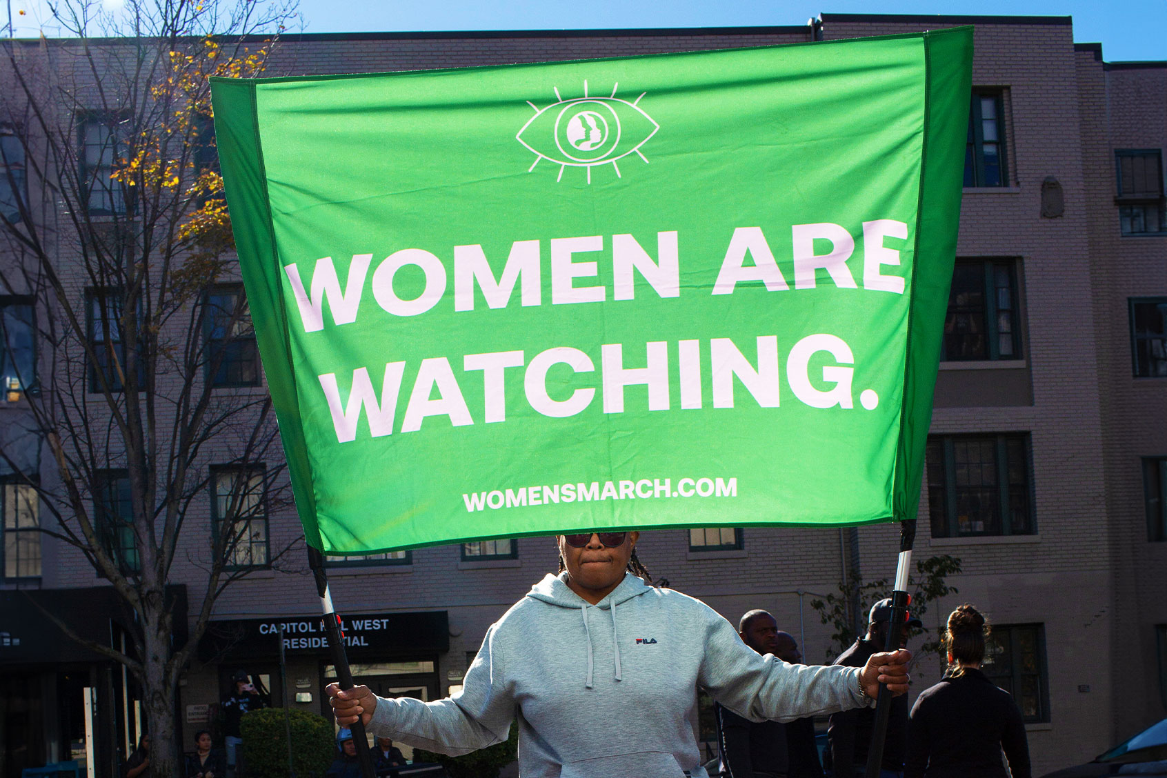 An abortion rights activist holding a sign with Women are Waching is written on it, gathers in front of the Heritage Foundation during the Women's March on November 09, 2024. (Probal Rashid/LightRocket via Getty Images)