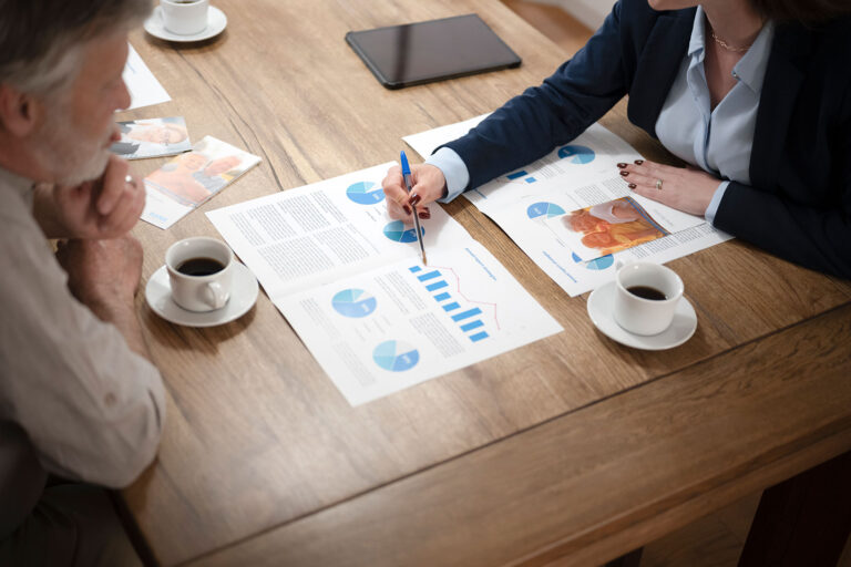 Senior man discussion with financial advisor while sitting at dining table in house (Getty Images/simonkr)