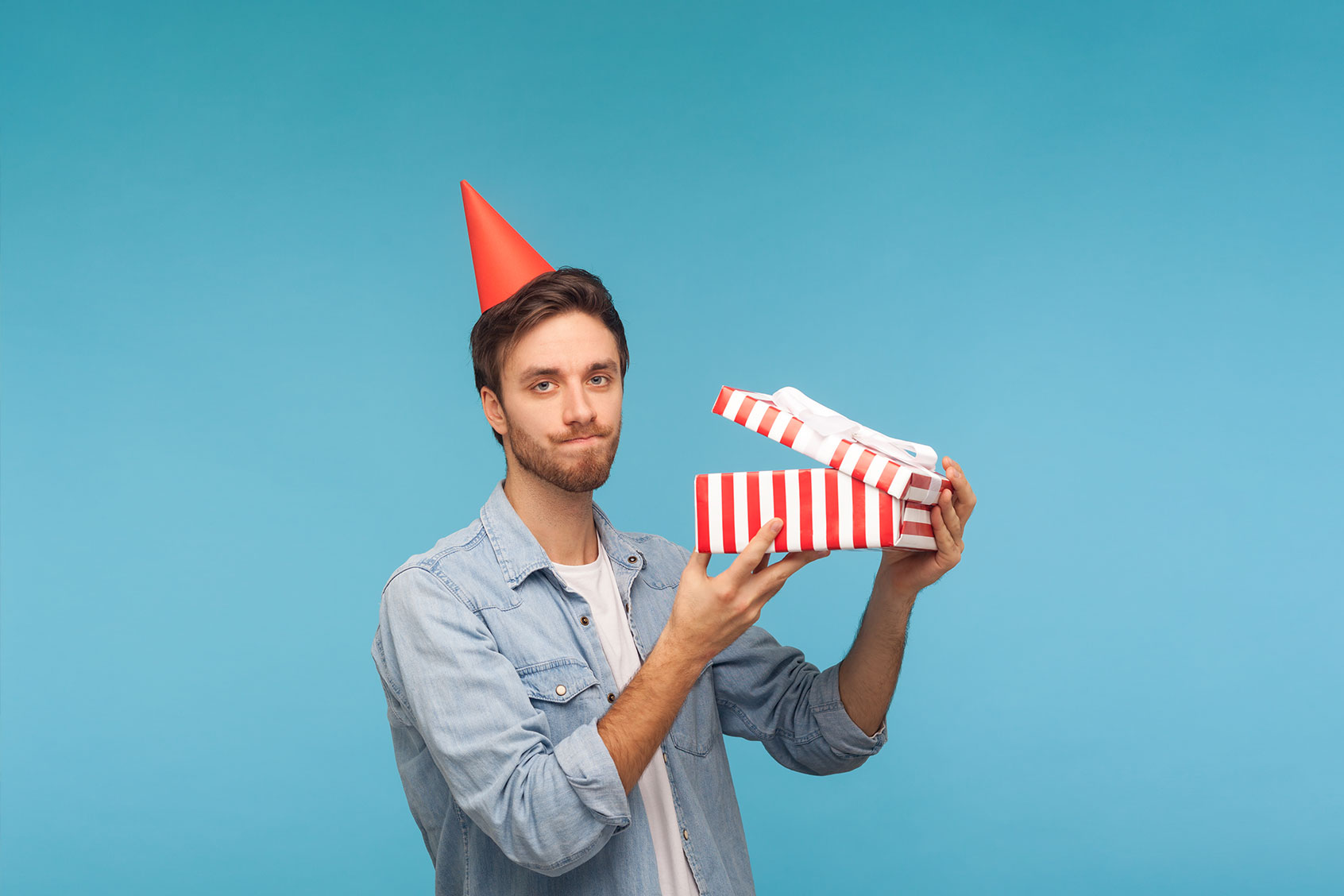 Frustrated man with party hat holding opened gift box (Getty Images/Khosrork)