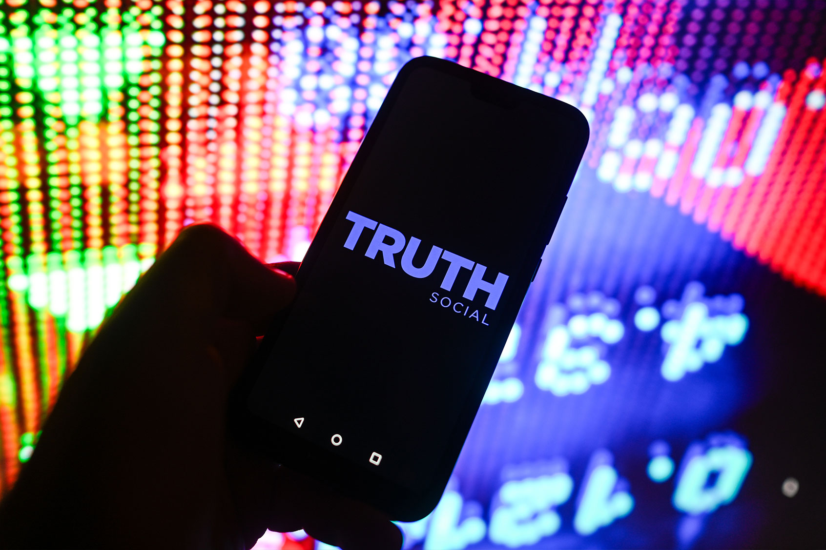 The Truth Social logo is displayed on a smartphone with Stock market values in the background. (Illustration by Omar Marques/SOPA Images/LightRocket via Getty Images)