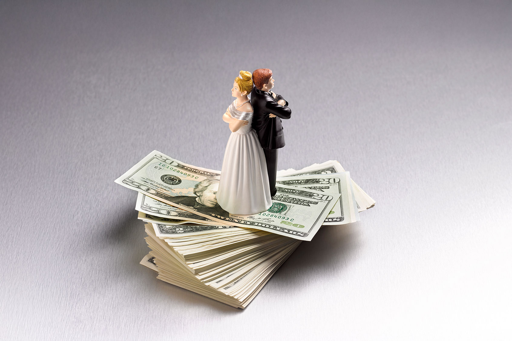 Wedding figurine couple back to back on a pile of US dollars (Getty Images/Peter Dazeley)
