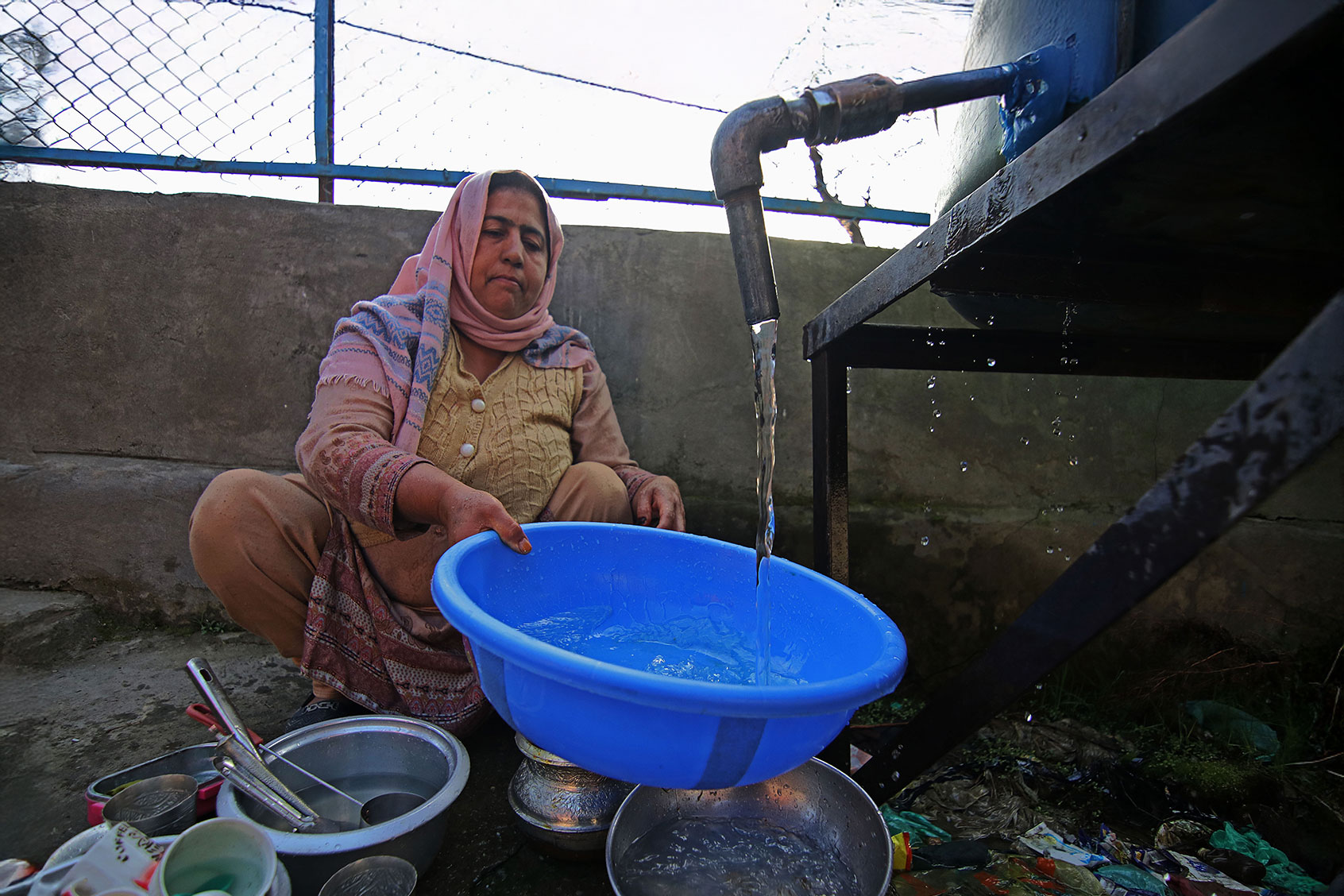 A woman washes utensils at a water supply station on the World Water Day in north Kashmir's Baramulla district on March 22, 2023. (Faisal Khan/Anadolu Agency via Getty Images)