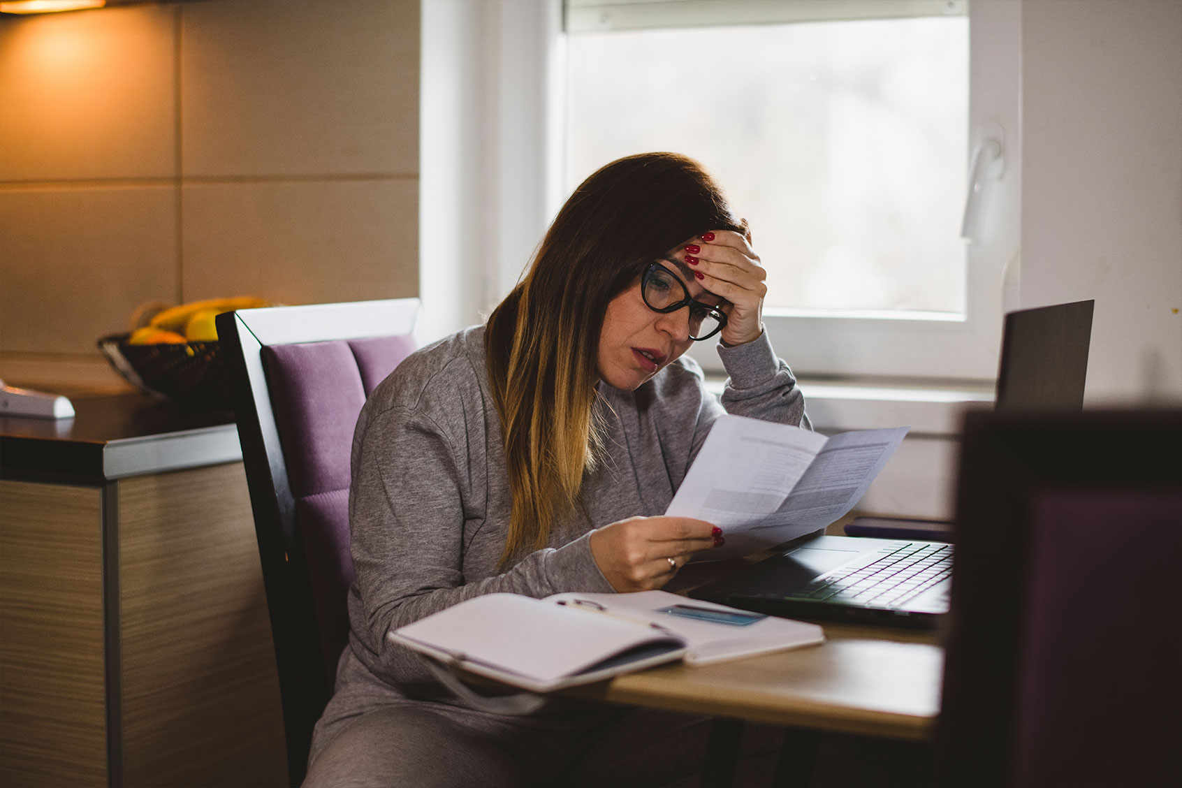 Woman worriedly looking at her bills (Getty Images/dmphoto)