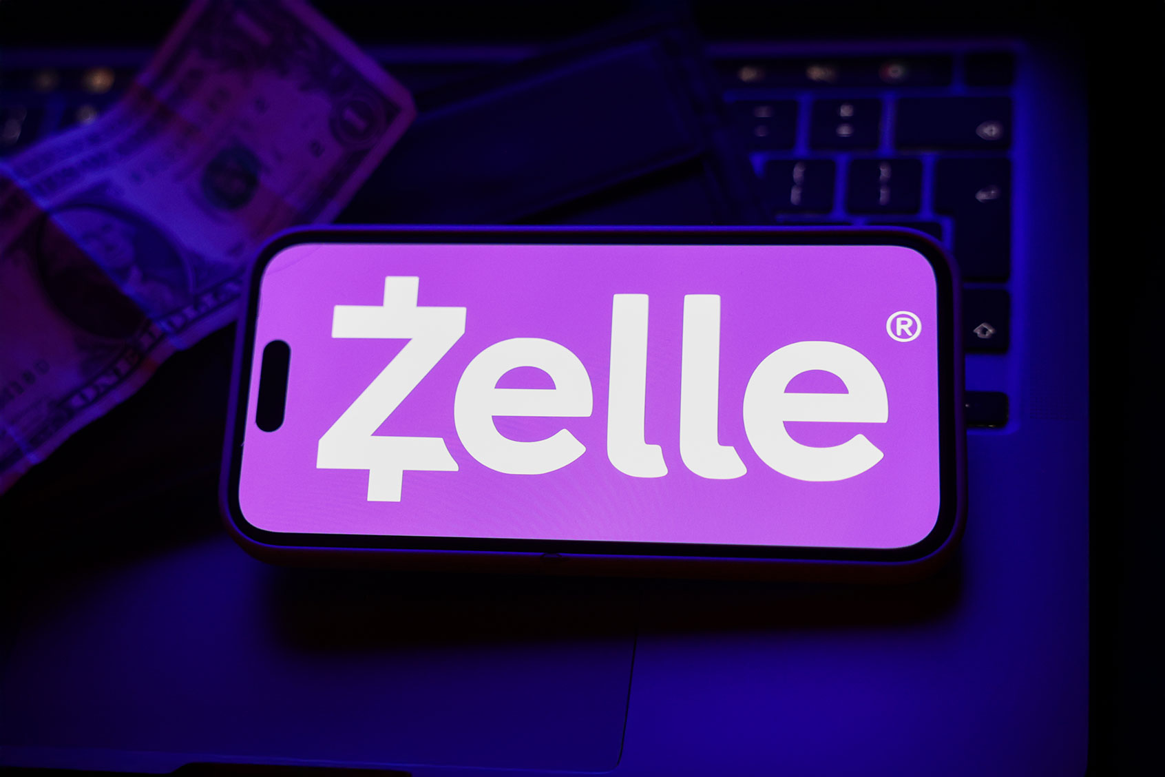 A laptop keyboard, a banknote, a wallet and Zelle logo displayed on a phone screen are seen in this illustration photo taken in Krakow, Poland on October 23, 2024. (Jakub Porzycki/NurPhoto via Getty Images)
